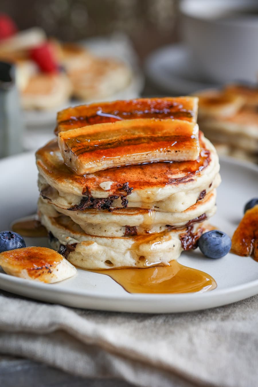 Stack of banana chocolate chunk pancakes topped with fresh berries